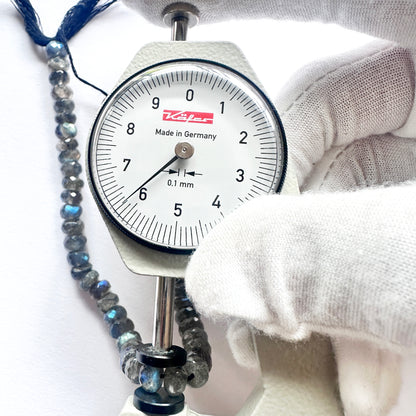 A dial gauge measures the Labradorite faceted rondelle  gemstone.