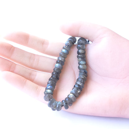 A person holds delicate strands of Labradorite beads, showcasing their Faceted Rondelle design.