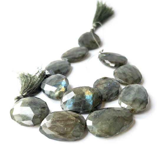 Labradorite faceted oval gemstone beads arranged in a set showing blue‑gold flashes and polished facets.