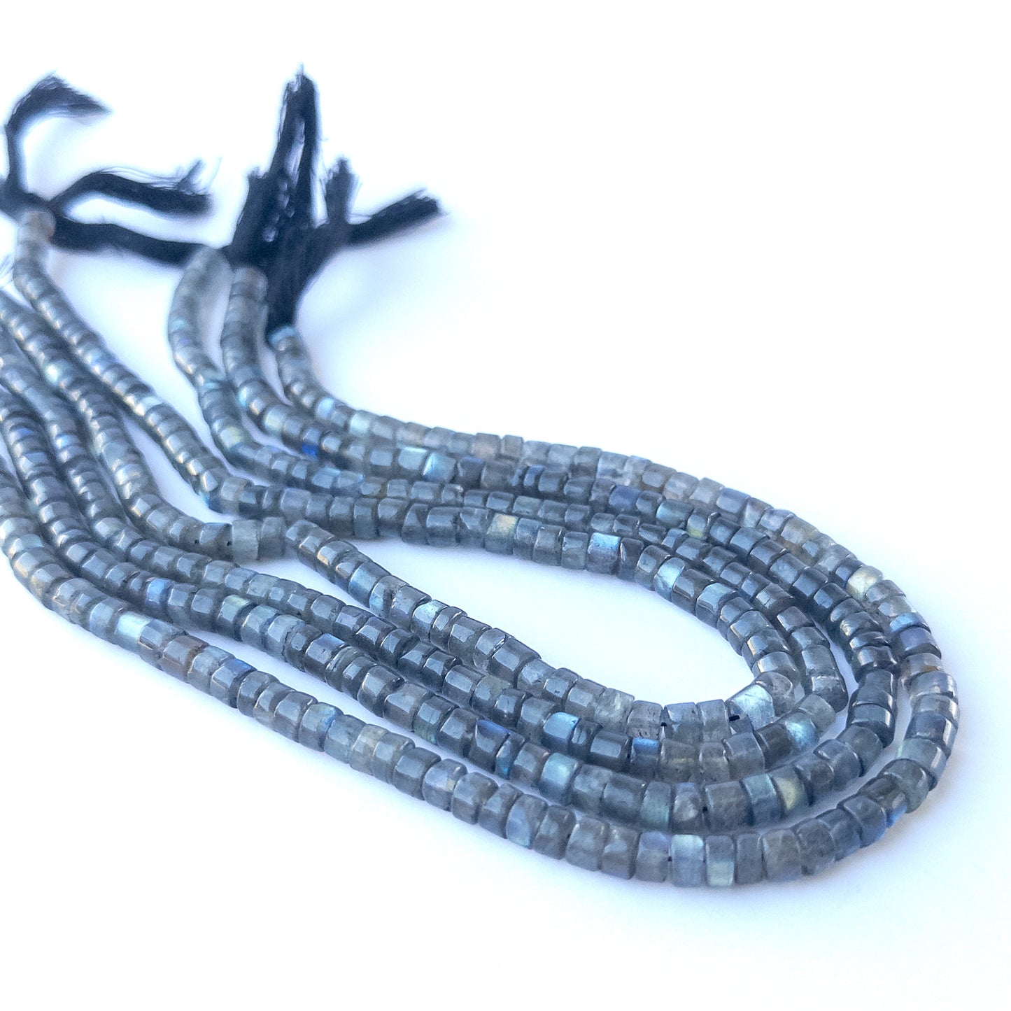Close‑up of genuine Labradorite smooth cylinder beads showing their shine, flash, and precise 5.5–5.7mm cut.