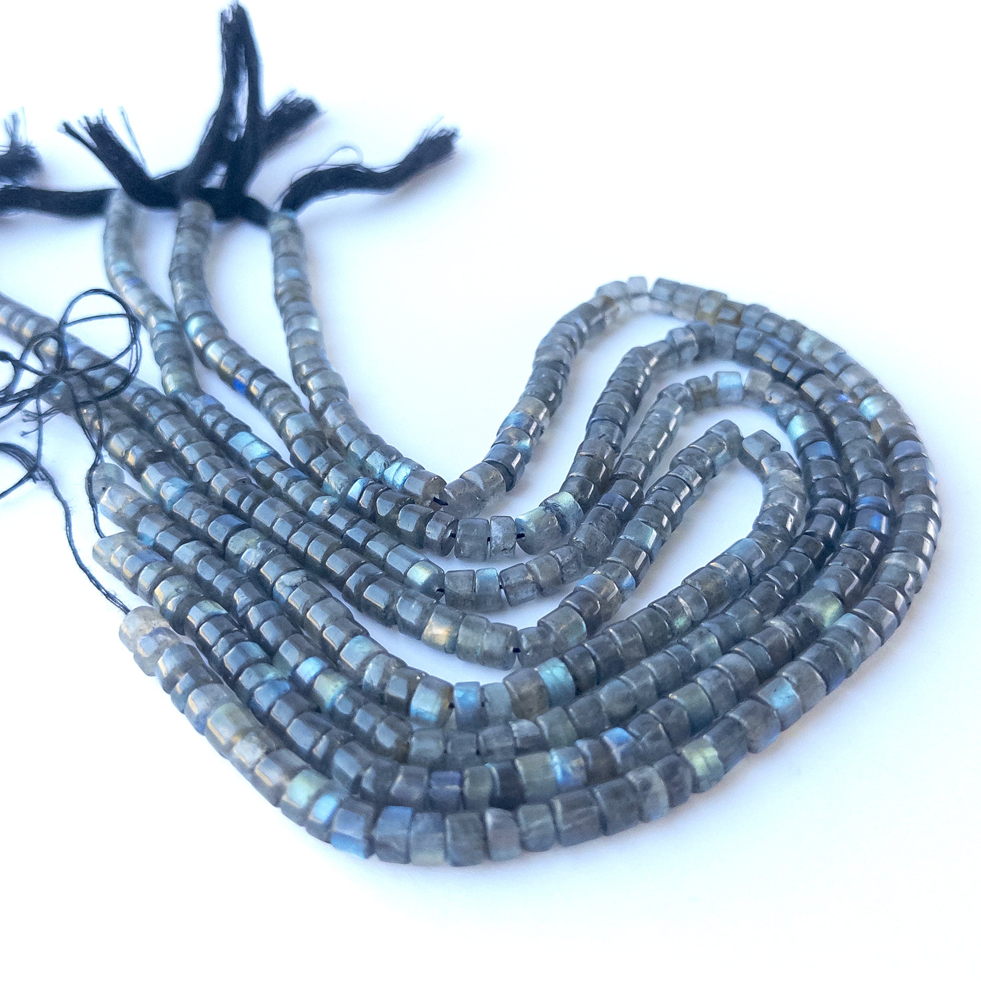 delicate strands of Labradorite beads, showcasing their smooth cylinder design and sparkle.  
