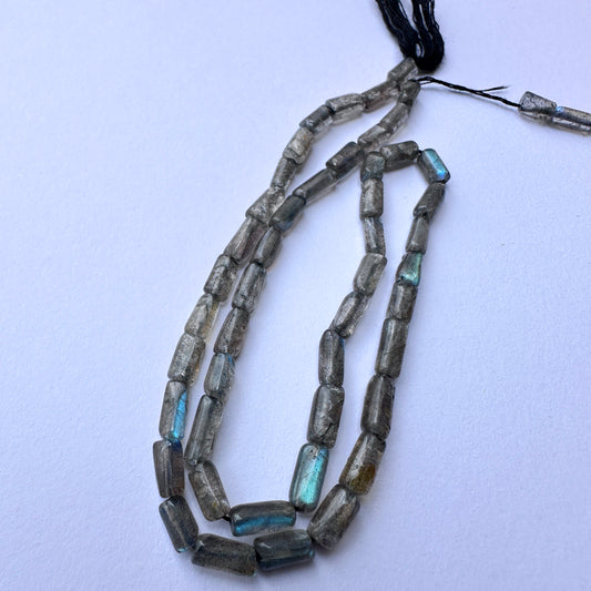 Smooth labradorite stone beads with subtle blue flashes and sleek cylindrical cut for handmade jewellery components.