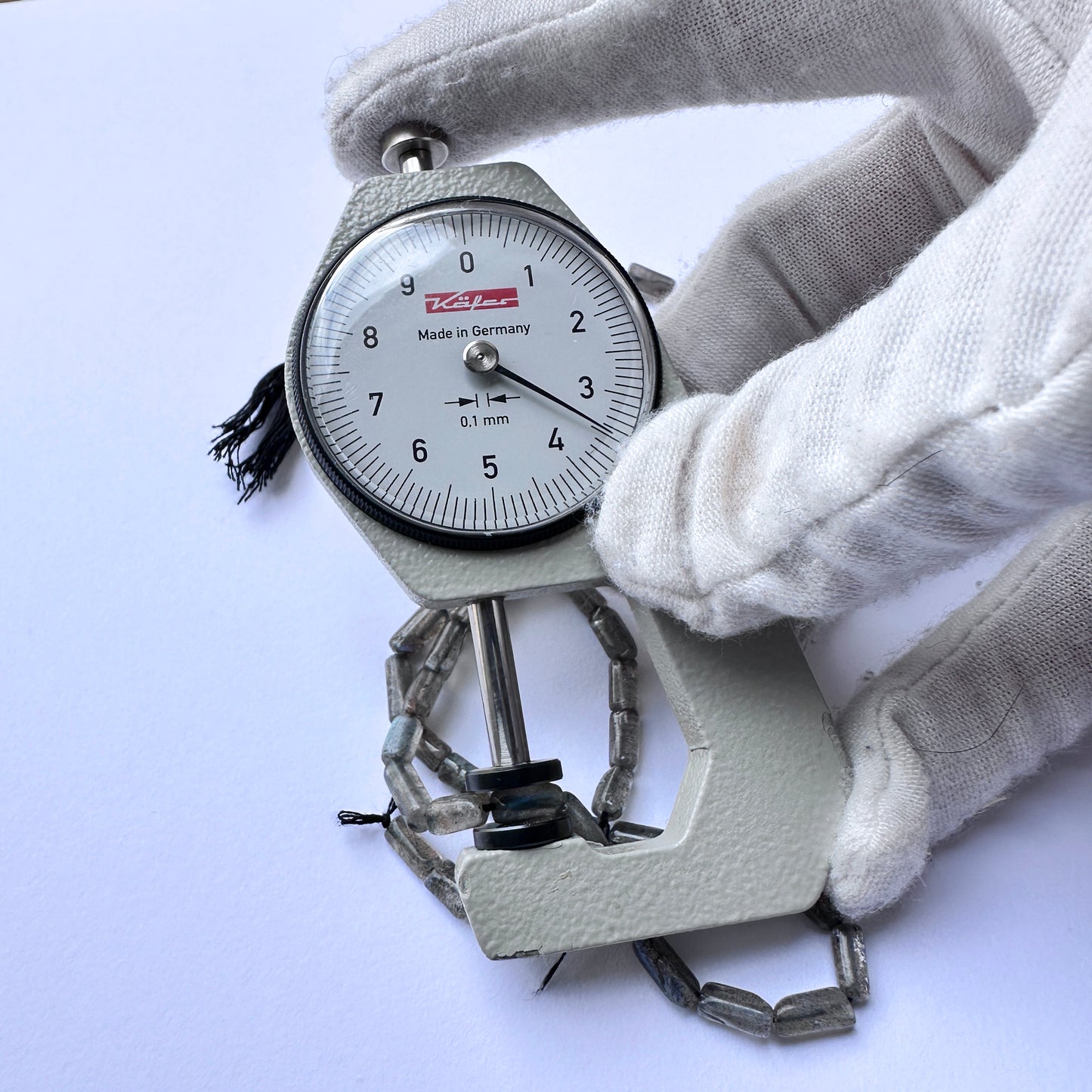 A dial gauge measures the labradorite pipe-shaped gemstone.