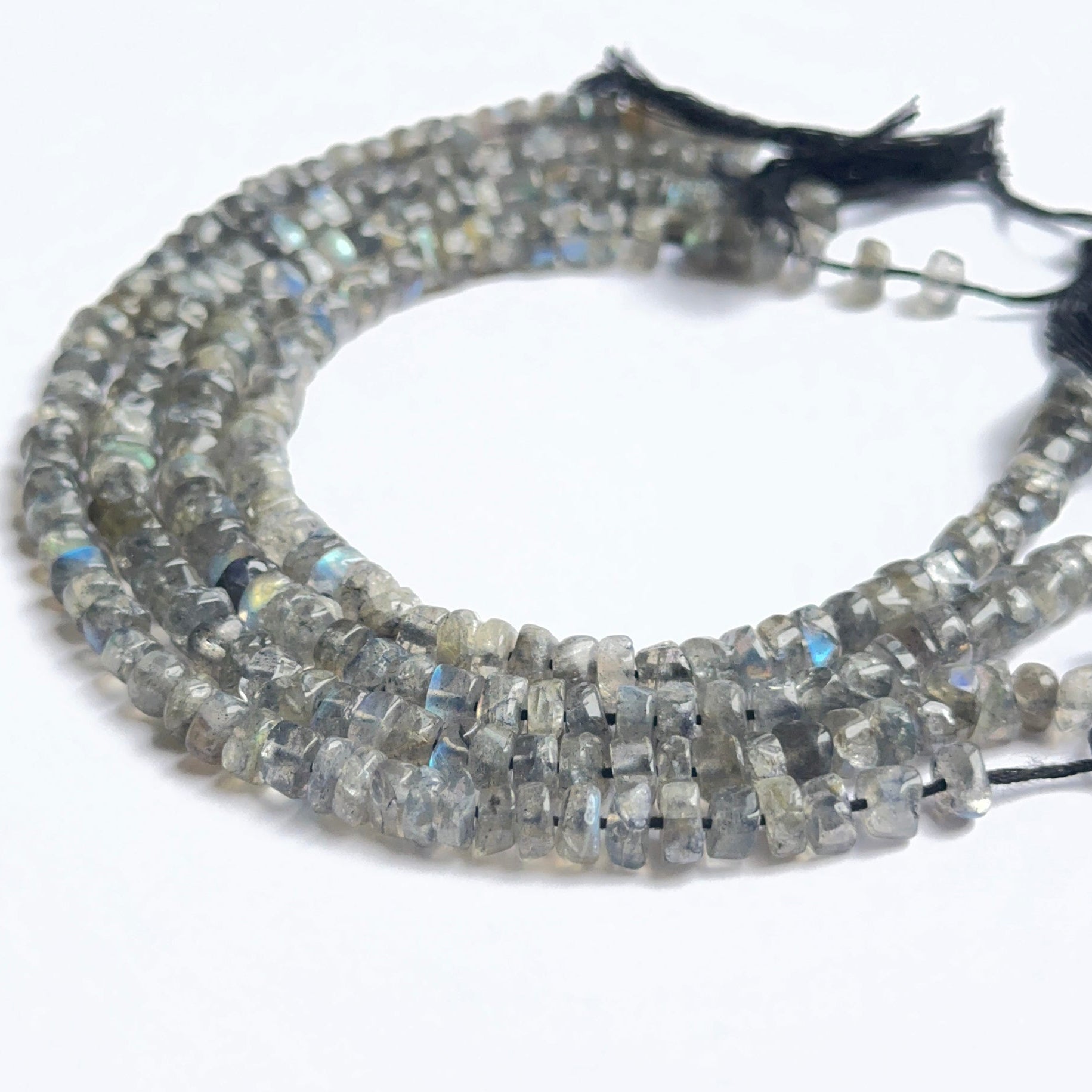 Close‑up of labradorite smooth wheel heishi beads highlighting their glossy finish and blue‑green sheen.