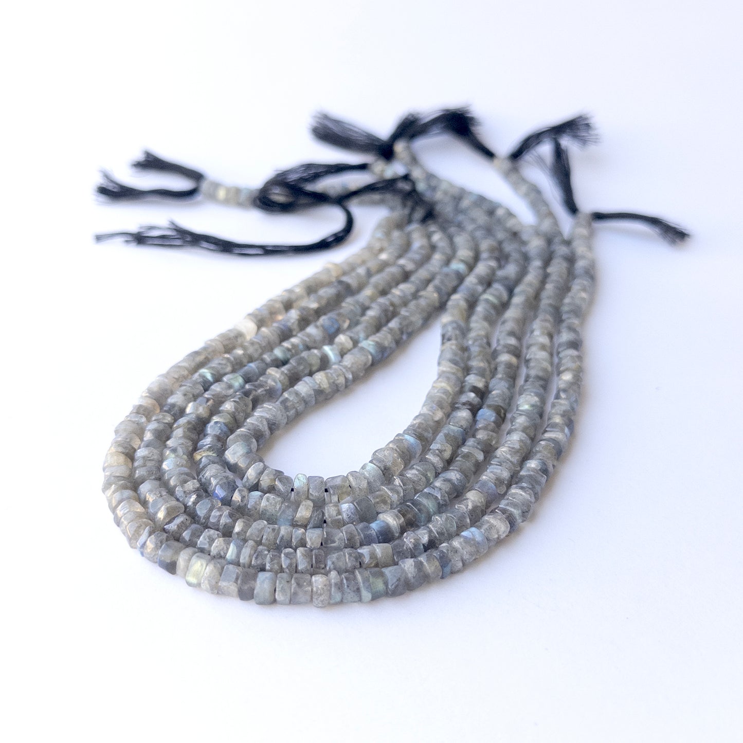 Genuine Labradorite gemstone beads displaying grey tones with blue flash, polished surfaces, and a neatly arranged strand for jewellery design.