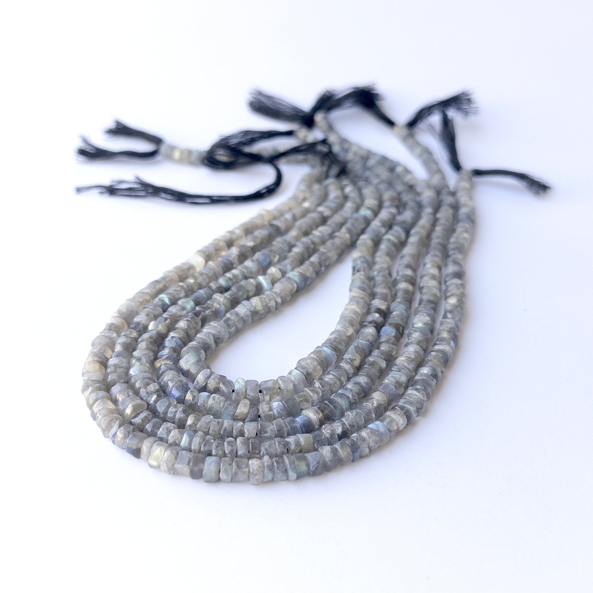 Genuine Labradorite gemstone beads displaying grey tones with blue flash, polished surfaces, and a neatly arranged strand for jewellery design.