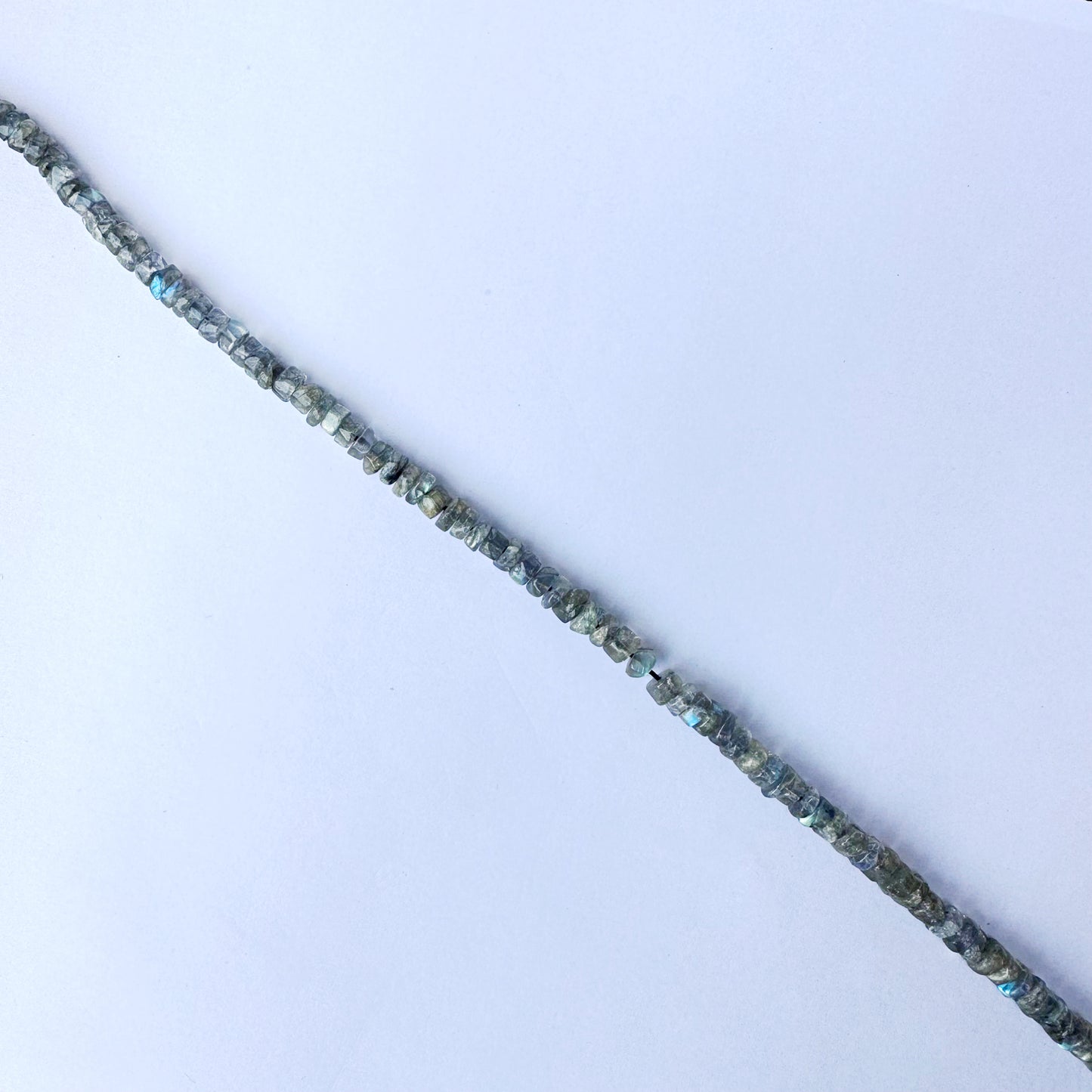 Labradorite beads arranged in a neat strand, highlighting their smooth wheel cut and shine.