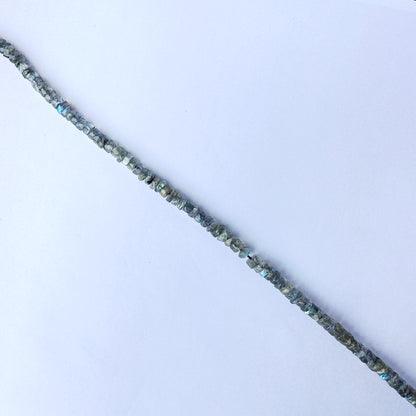 Labradorite beads arranged in a neat strand, highlighting their smooth wheel cut and shine.