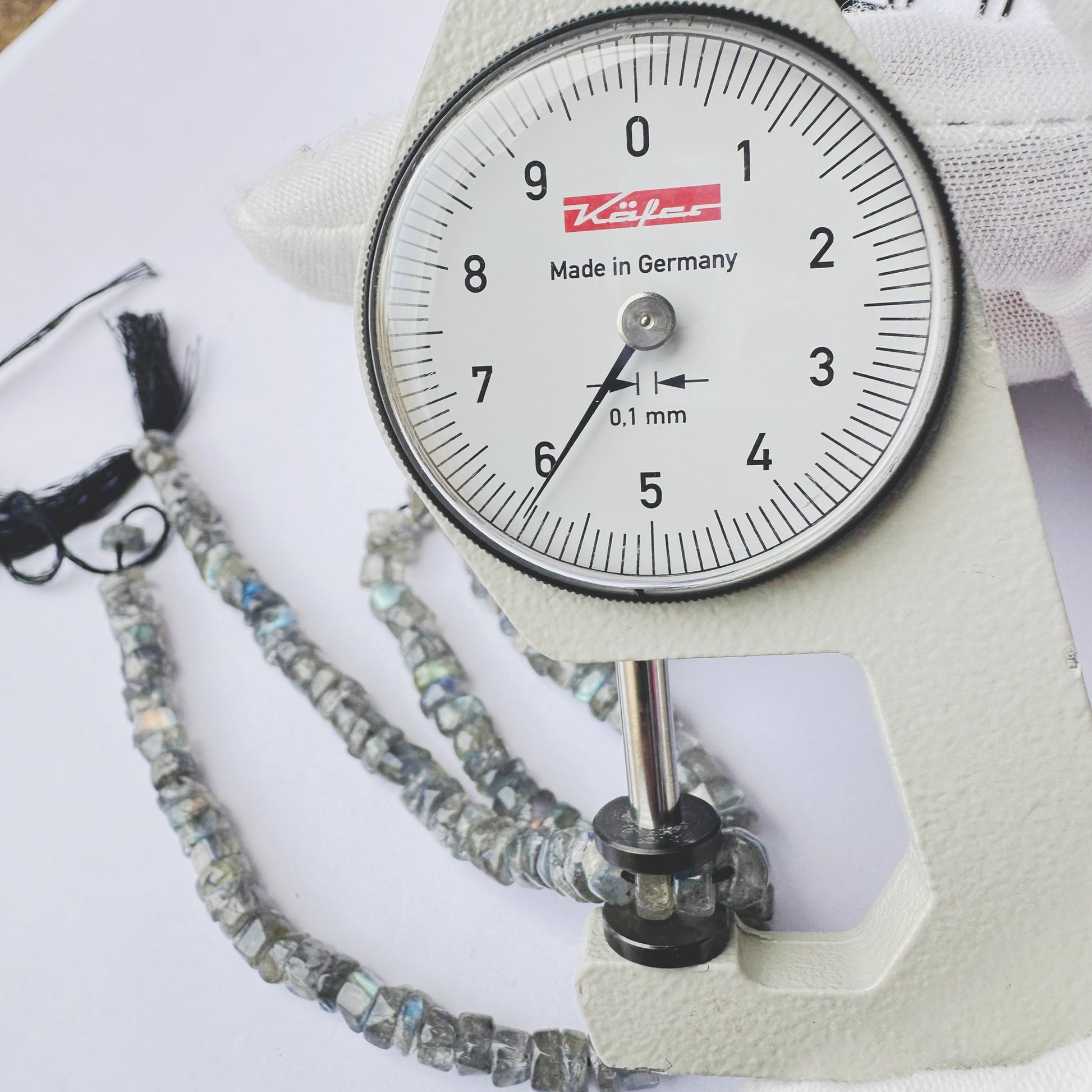A dial gauge measures the Labradorite smooth wheel 5.5mm gemstone.
