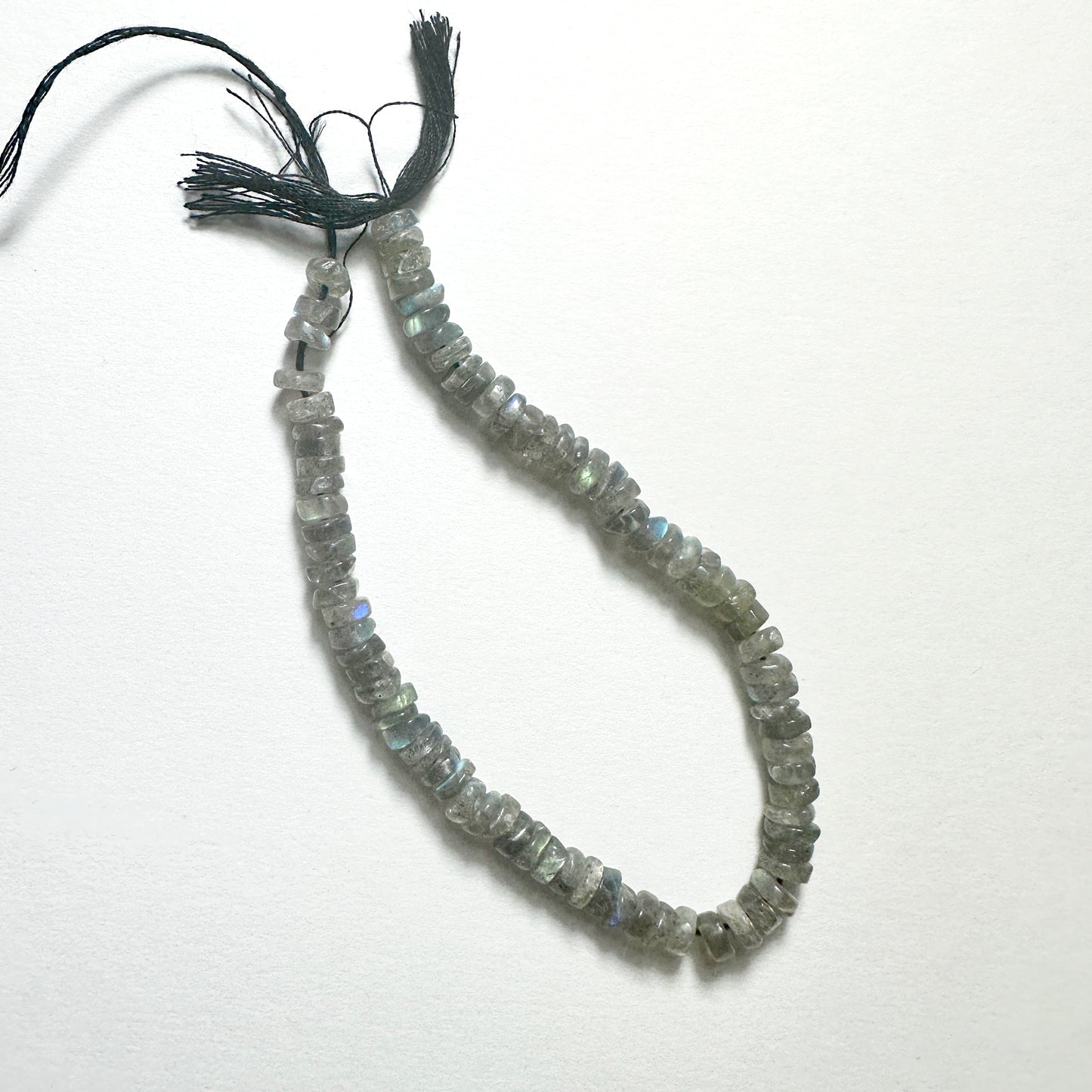 Close-up of Labradorite stone beads with smooth wheel cut, showcasing blue and green flashes for handmade jewellery components.