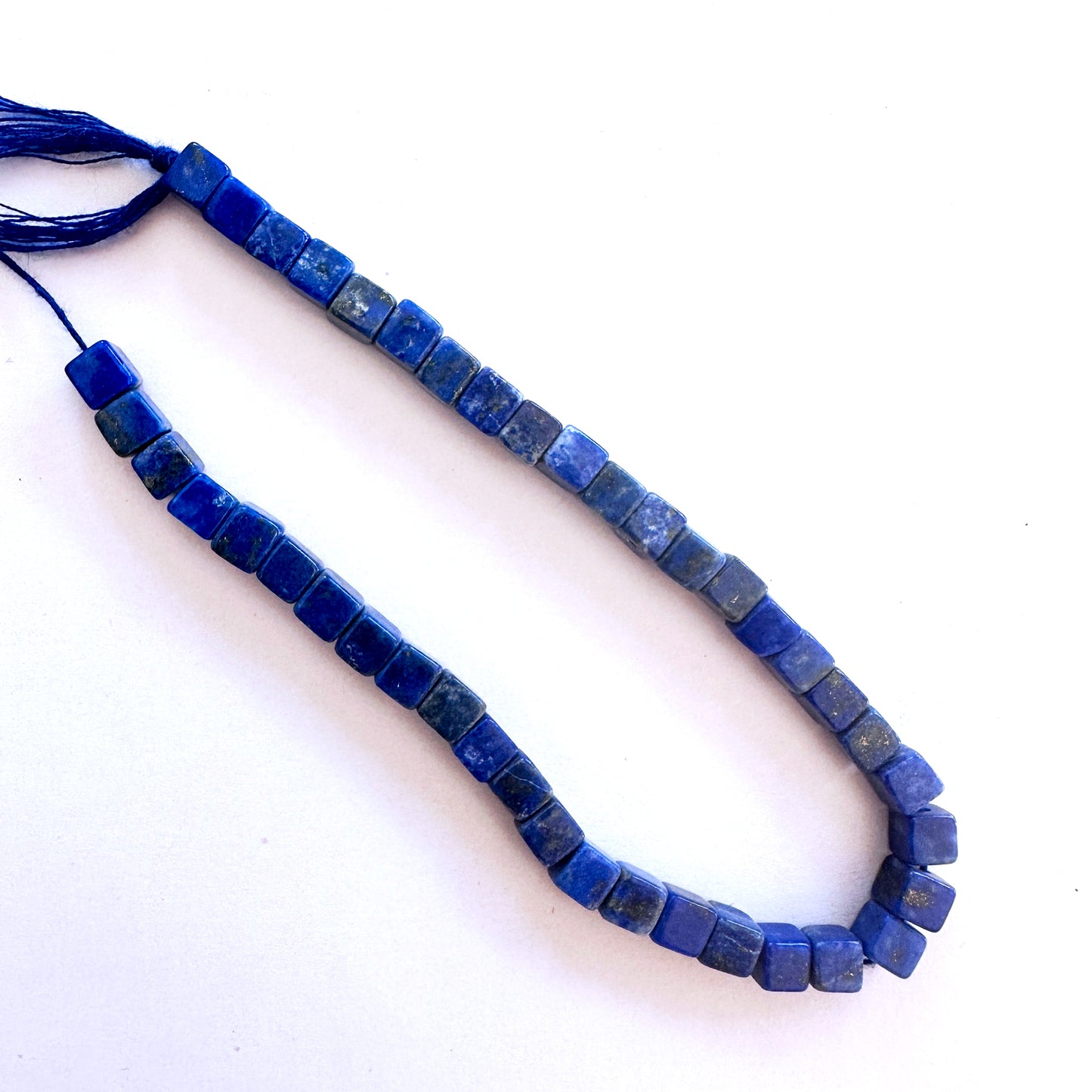 A dial gauge measures the Lapis Lazuli smooth cube 5mm gemstone.