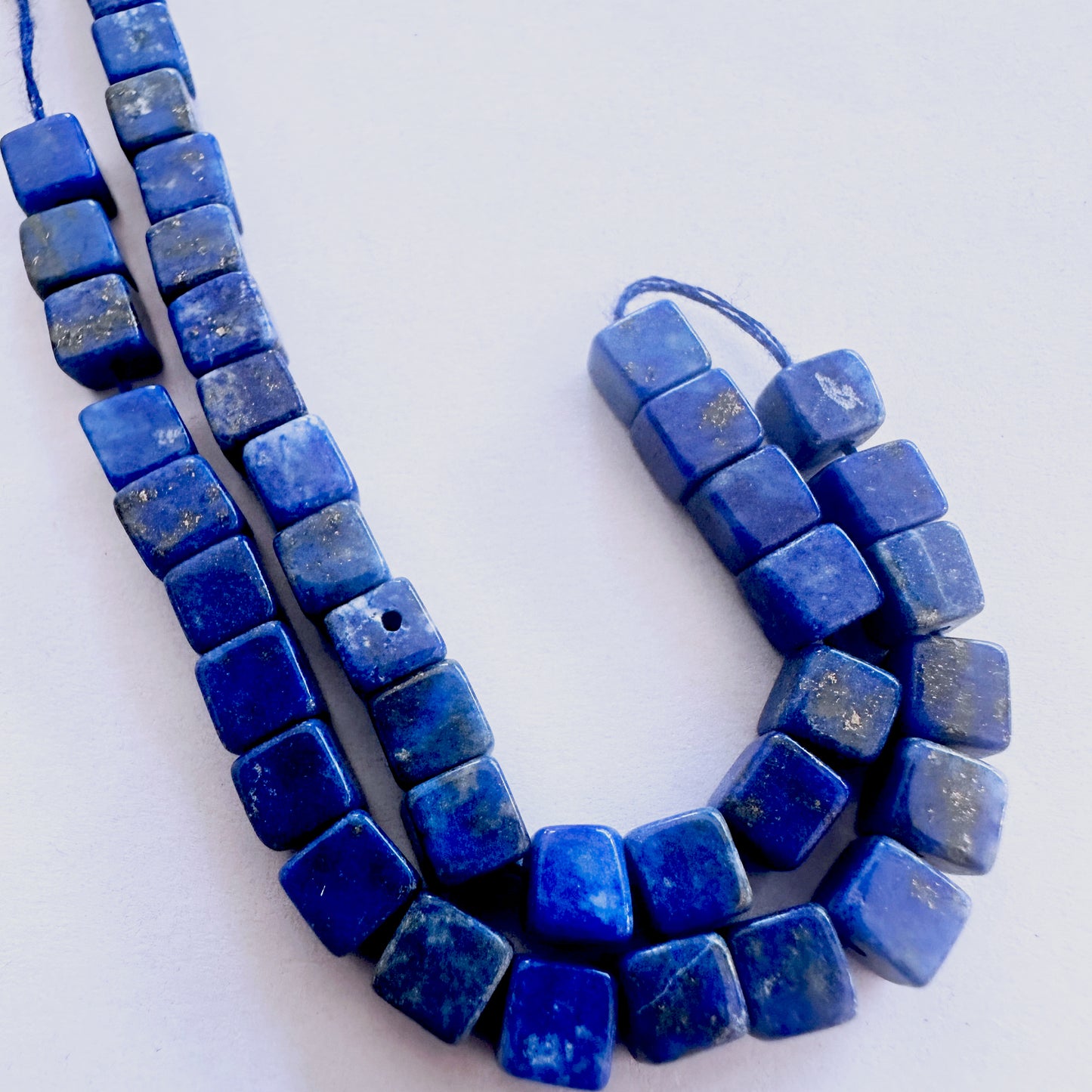 Lapis Lazuli cube-cut beads with deep blue colour and polished surface arranged neatly across a short strand.