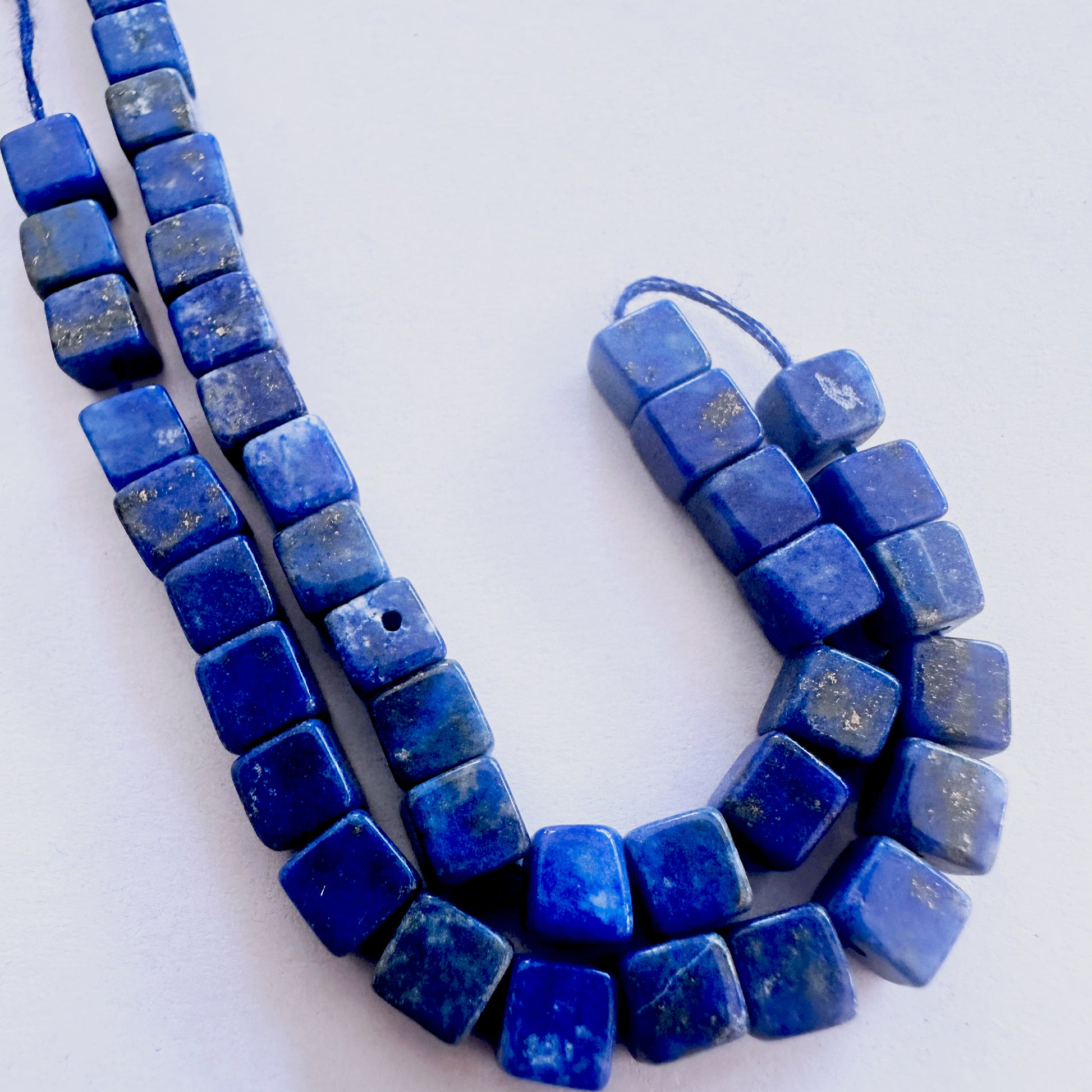 Lapis Lazuli cube-cut beads with deep blue colour and polished surface arranged neatly across a short strand.