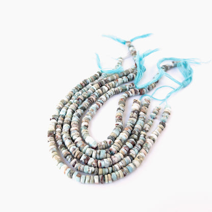 Larimar smooth wheel beads in soft blue tones arranged on a strand for handmade jewellery components.