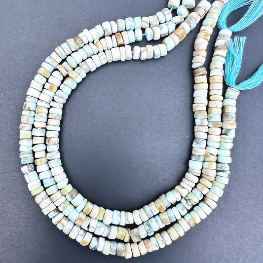 Close-up of Larimar smooth wheel beads with sky-blue and white marbled tones.