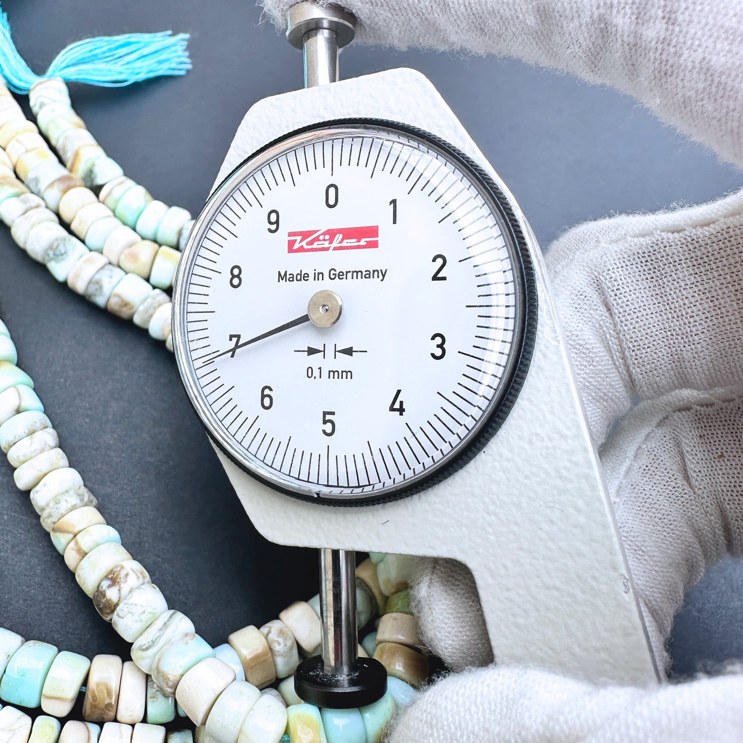 A dial gauge measures the Larimar smooth wheel 6.5-7.0mm gemstone.