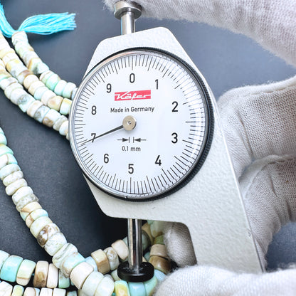 A dial gauge measures the Larimar smooth wheel 6.5-7.0mm gemstone.