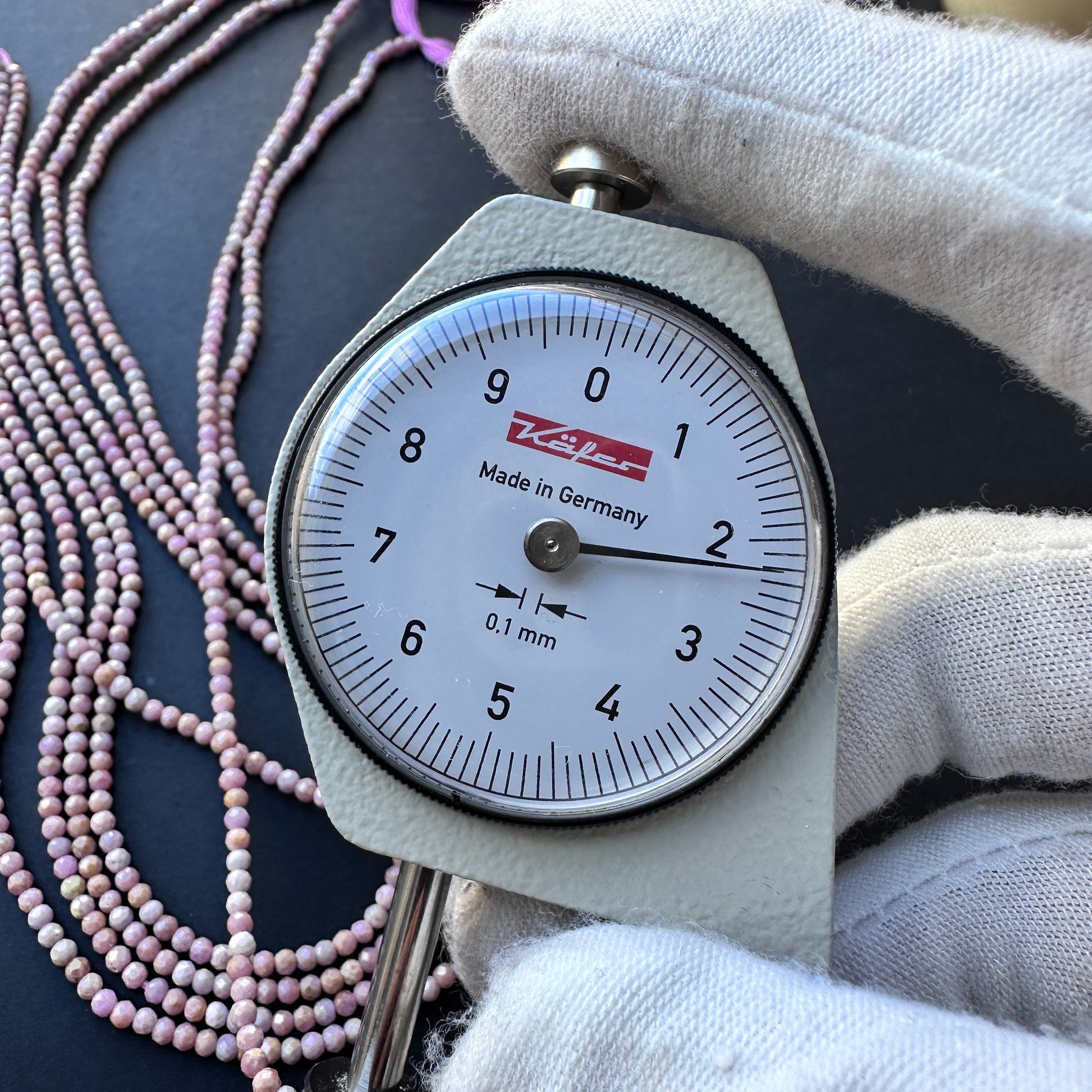 A dial gauge measures the Lavender Opal faceted rondelle 2.2mm gemstone.

