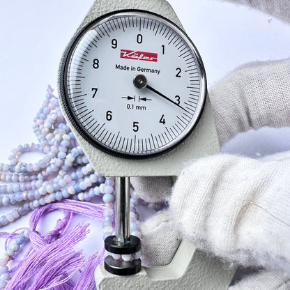 A dial gauge measures the lavender opal faceted rondelle 3.2mm gemstone.