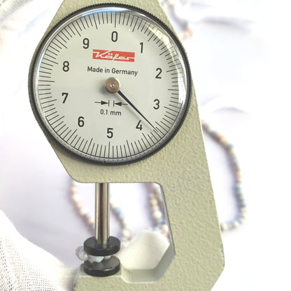 A dial gauge measures the Lavender Opal faceted rondelle 3.5-4mm gemstone.