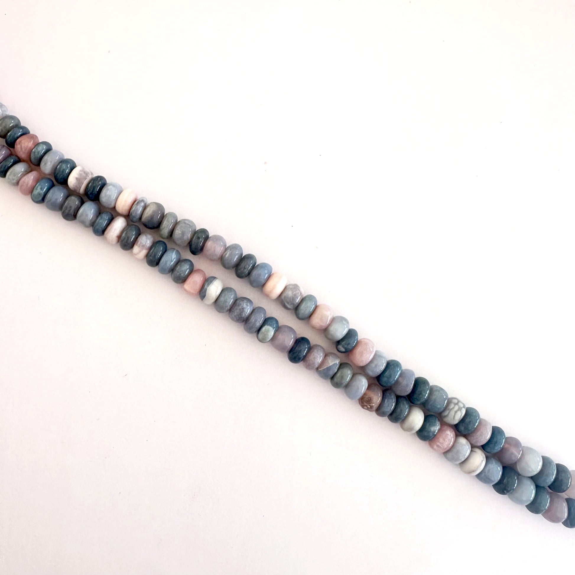 Lavender Opal beads laid out in rondelle formation showing natural variation and shine.