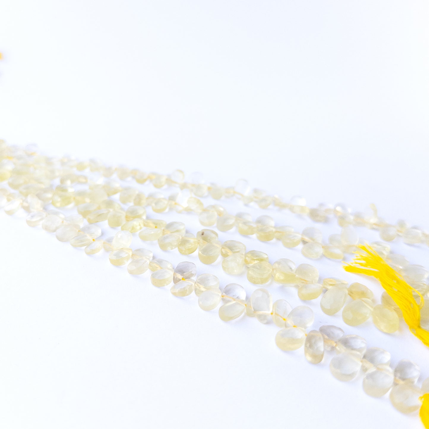Genuine Lemon Quartz faceted briolette gemstone beads with bright yellow sparkle arranged in a 20cm strand.