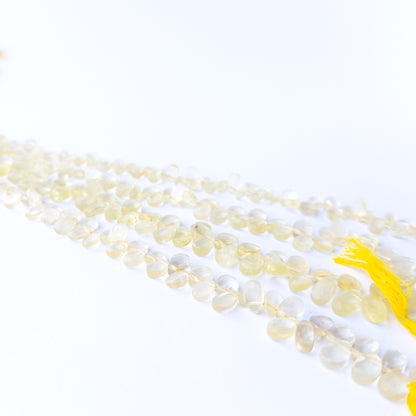 Genuine Lemon Quartz faceted briolette gemstone beads with bright yellow sparkle arranged in a 20cm strand.