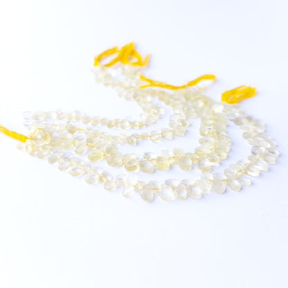 Lemon Quartz faceted briolette stone beads arranged neatly in a 20cm strand with glowing yellow tones.