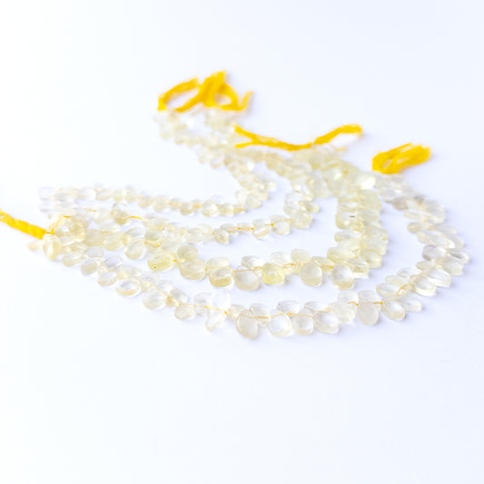 Lemon Quartz faceted briolette stone beads arranged neatly in a 20cm strand with glowing yellow tones.