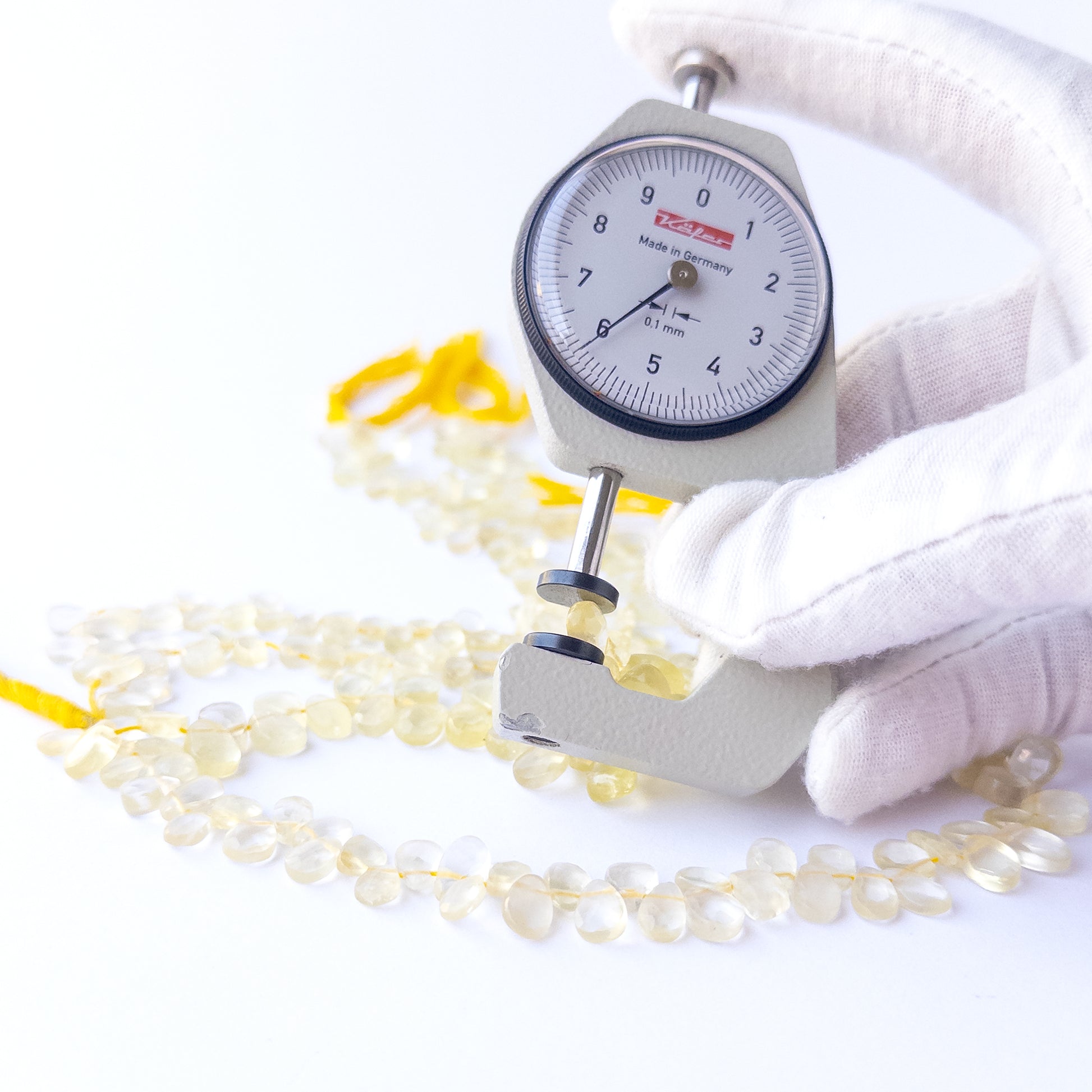 A dial gauge measures the Lemon Quartz faceted briolette 4.5–6.5mm gemstone.