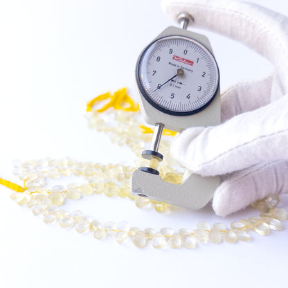 A dial gauge measures the Lemon Quartz faceted briolette 4.5–6.5mm gemstone.