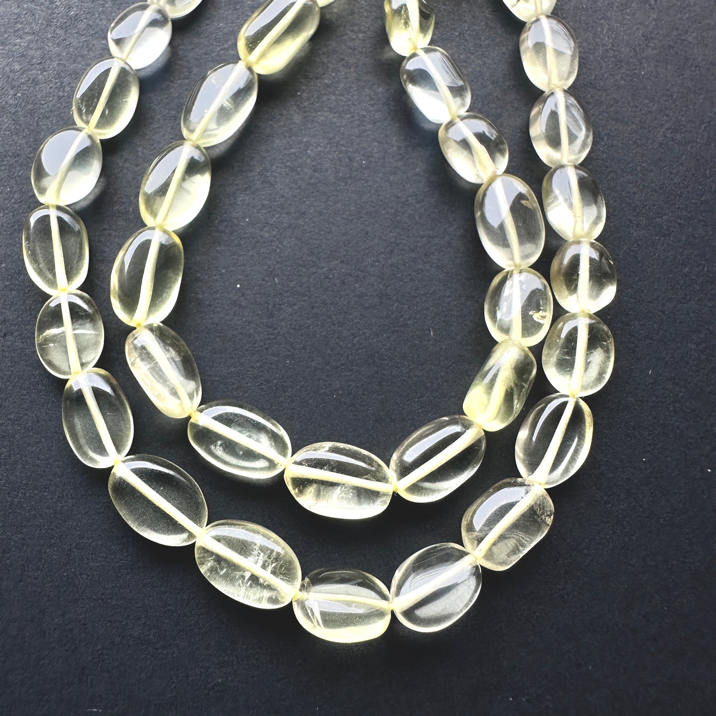Close-up of Lemon Quartz beads showcasing their bright colour and sleek oval shape.