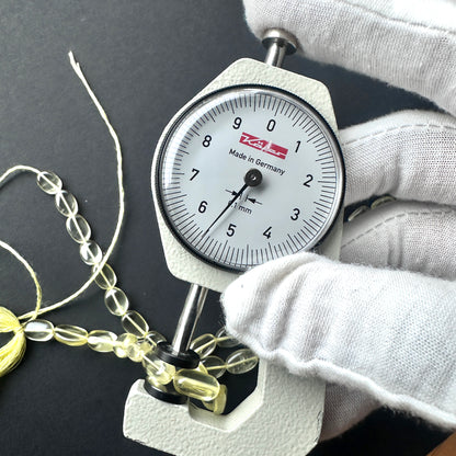 A dial gauge measures the Lemon Quartz smooth oval gemstone.
