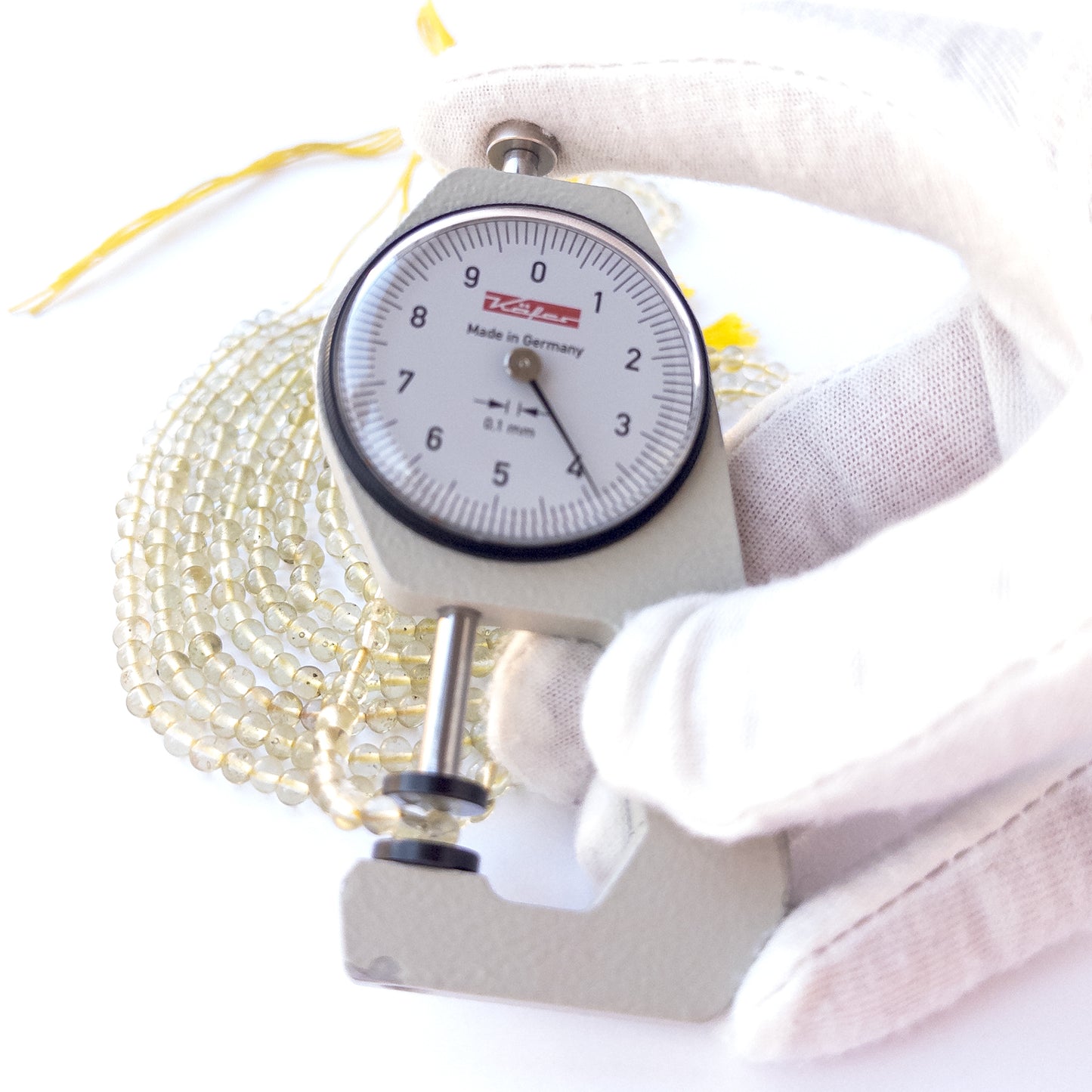 A dial gauge measures the Lemon Quartz smooth round 3.8–4mm gemstone.