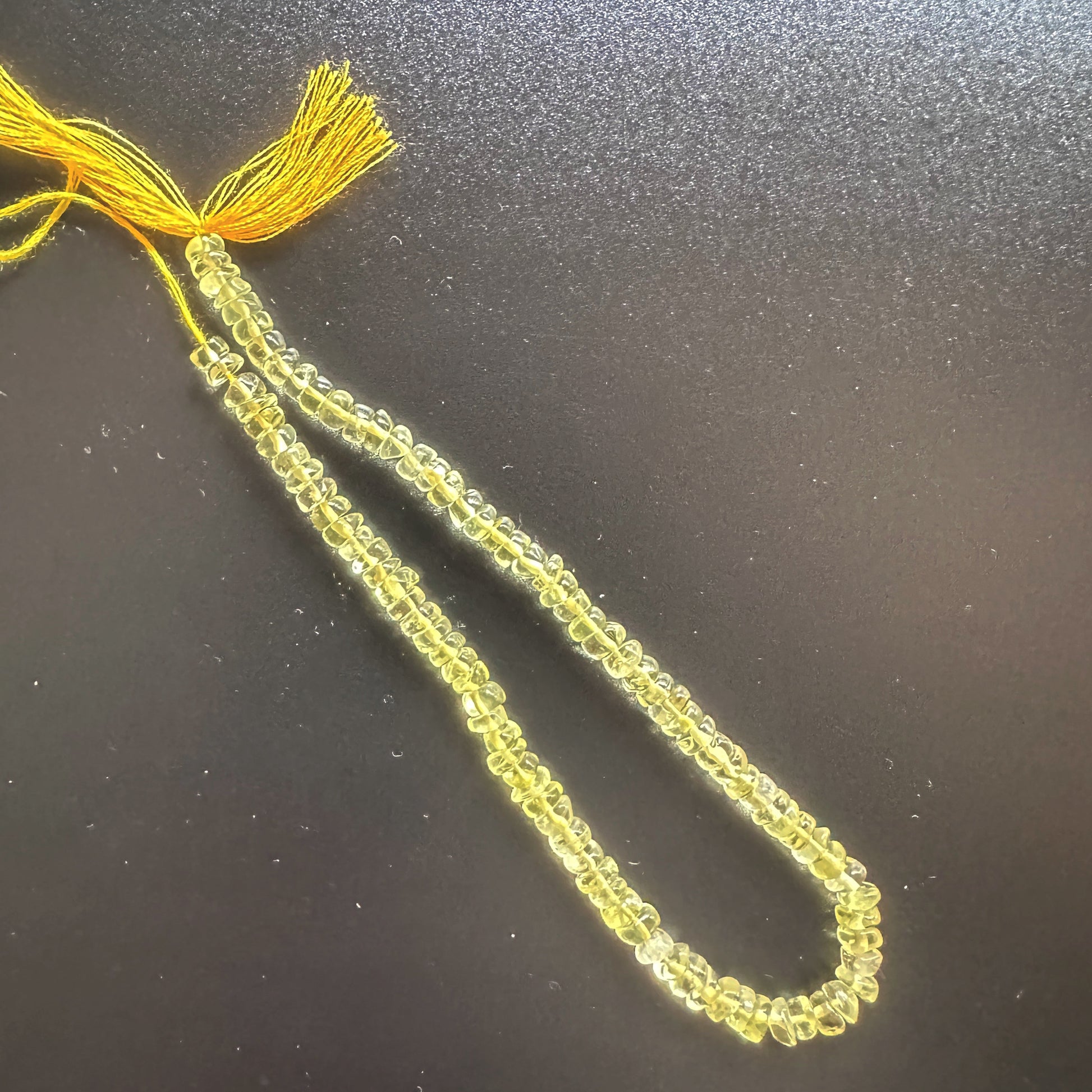 Close-up of Lemon Quartz beads arranged in a 21cm strand with glossy surface.