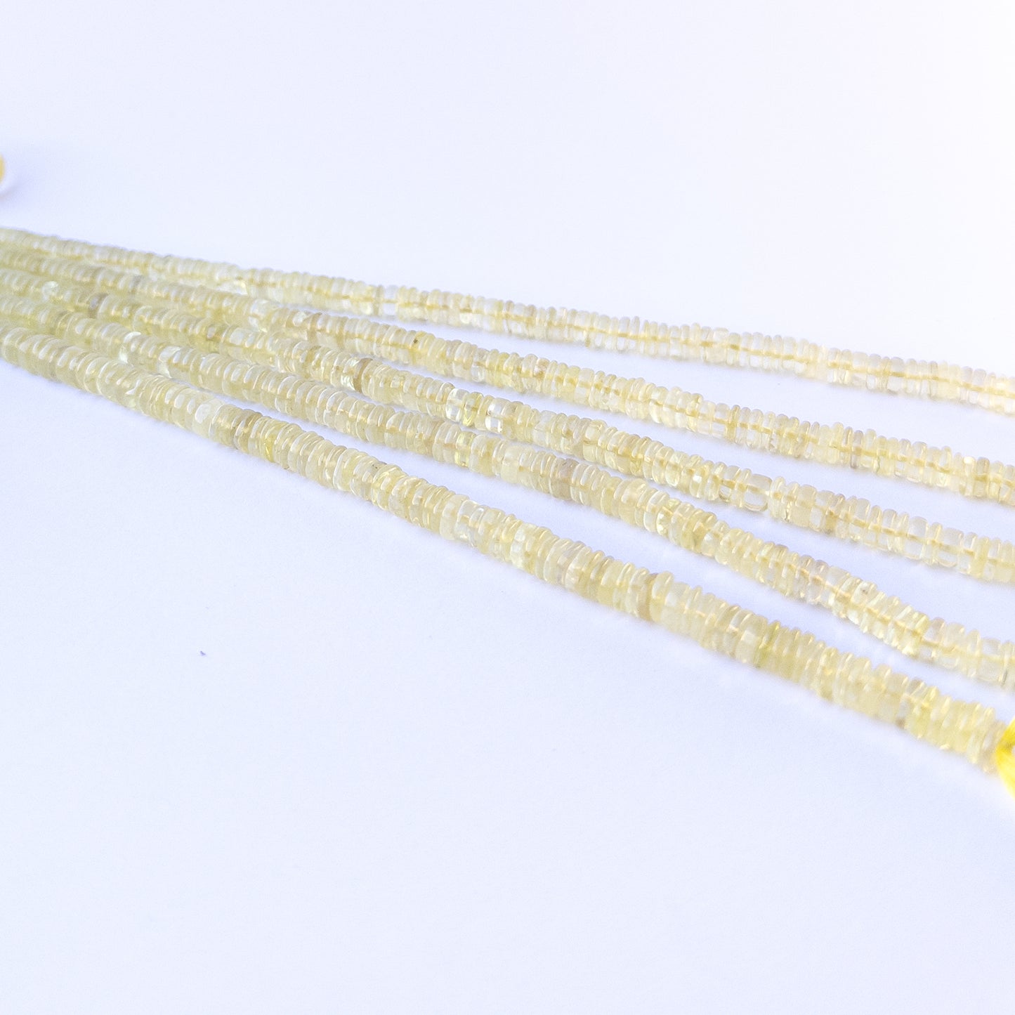 A person holds delicate strands of Lemon Quartz beads, showcasing their smooth wheel design.
