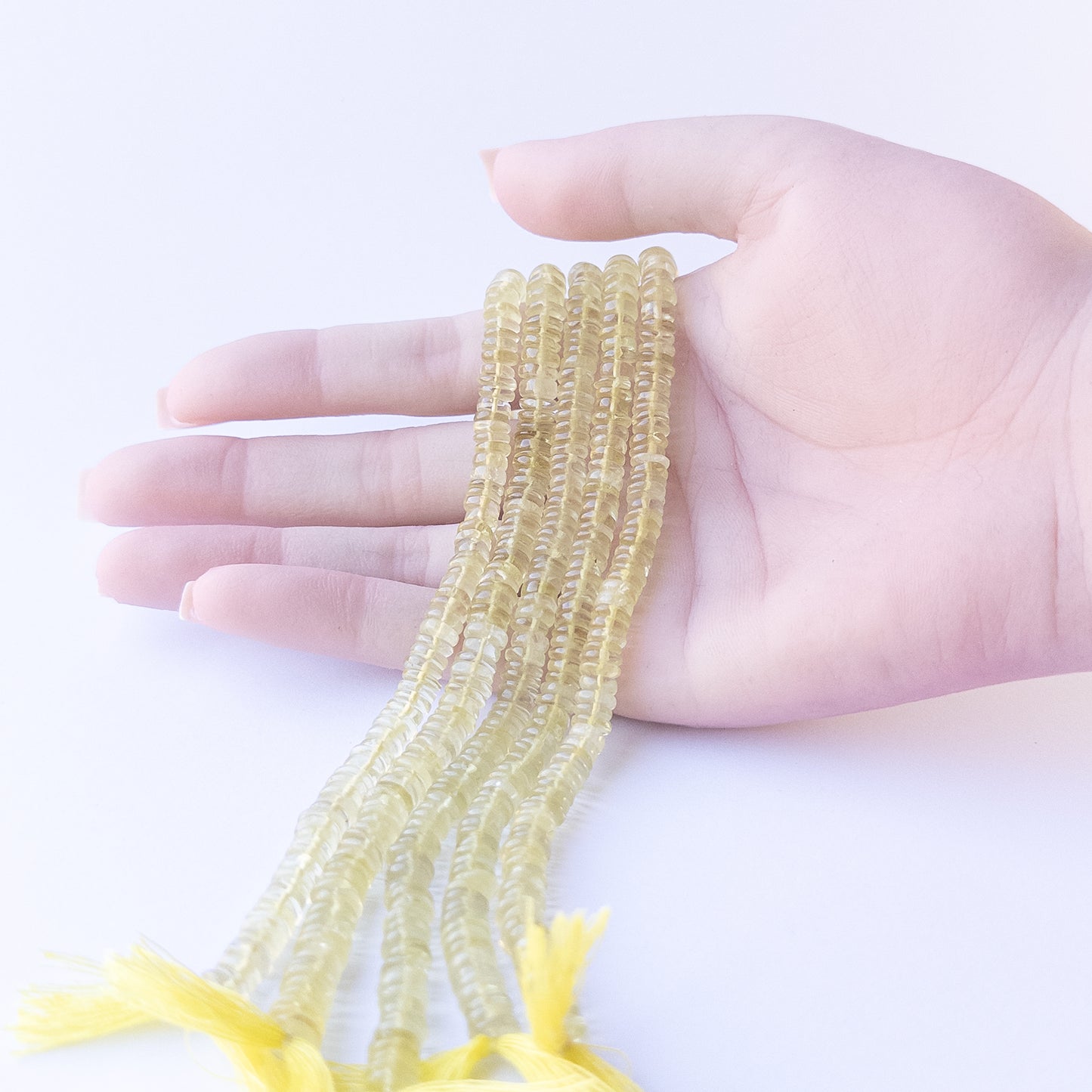 A coin is placed near delicate strands of Lemon Quartz beads for scale.