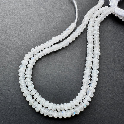 Moonstone faceted rondelle beads with pearly white tones and blue flashes arranged on a 13cm strand for jewellery making.