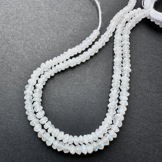 Moonstone faceted rondelle beads with pearly white tones and blue flashes arranged on a 13cm strand for jewellery making.
