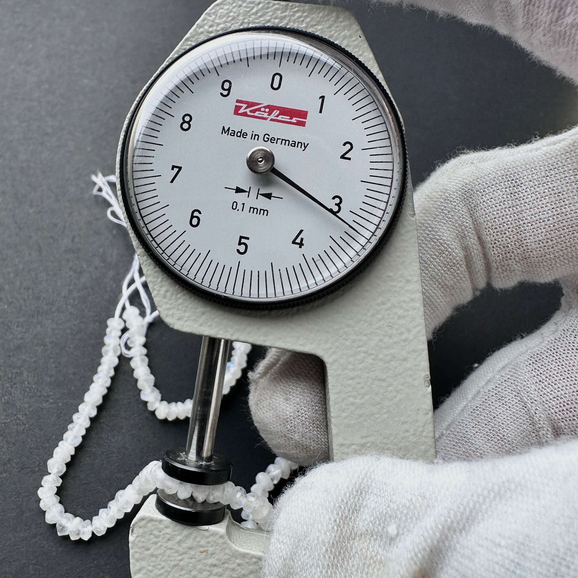 A dial gauge measures the Moonstone faceted rondelle 3.2mm gemstone.