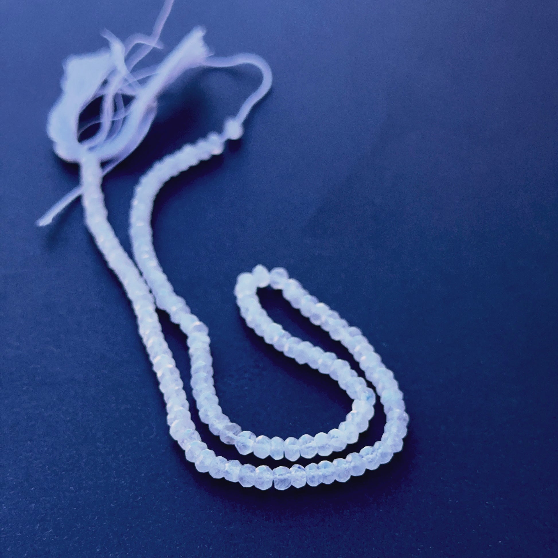 Moonstone faceted rondelle beads aligned on a strand highlighting clarity, cut quality and iridescent sheen.