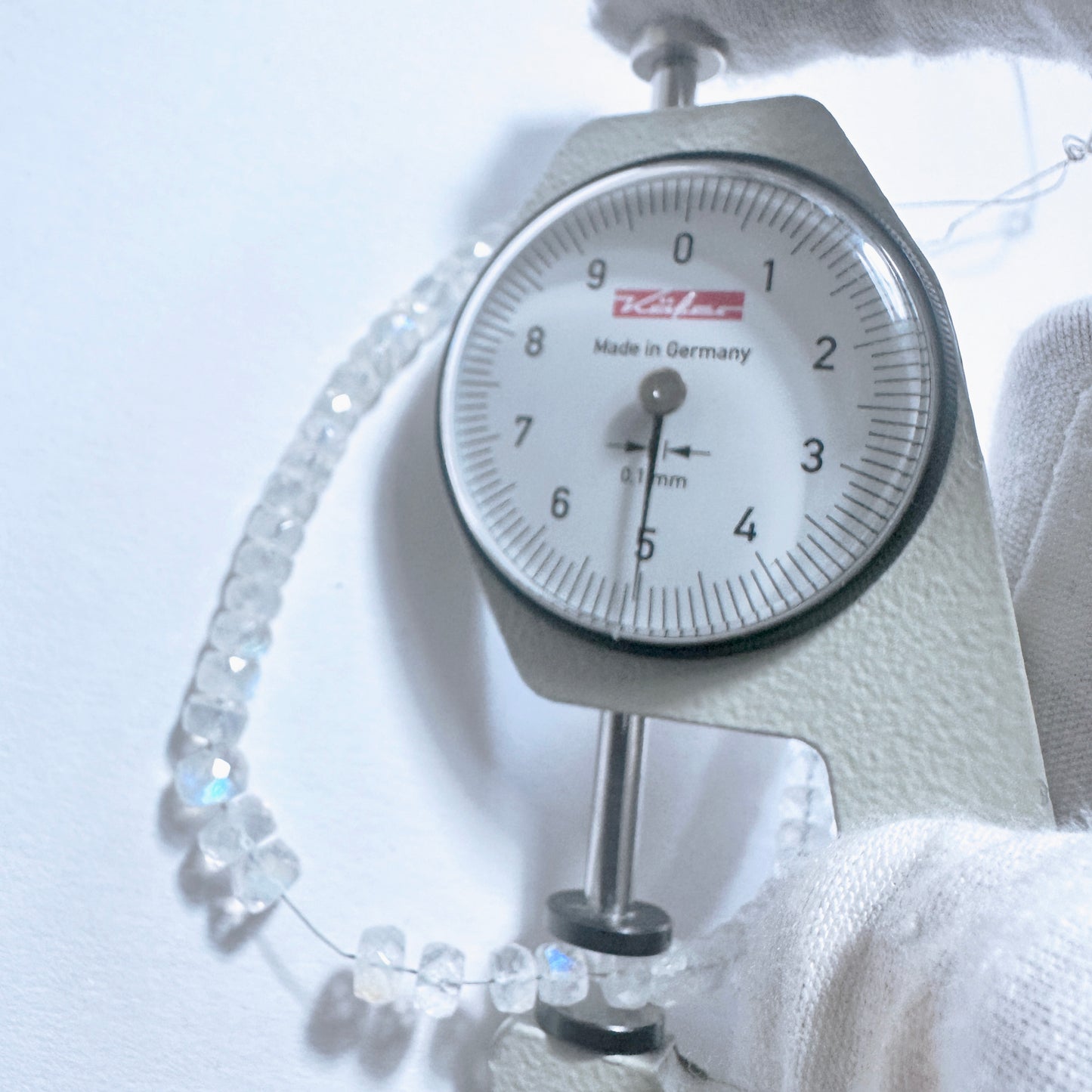 A dial gauge measures the Moonstone faceted rondelle gemstone.
