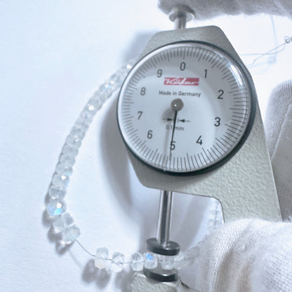 A dial gauge measures the Moonstone faceted rondelle gemstone.