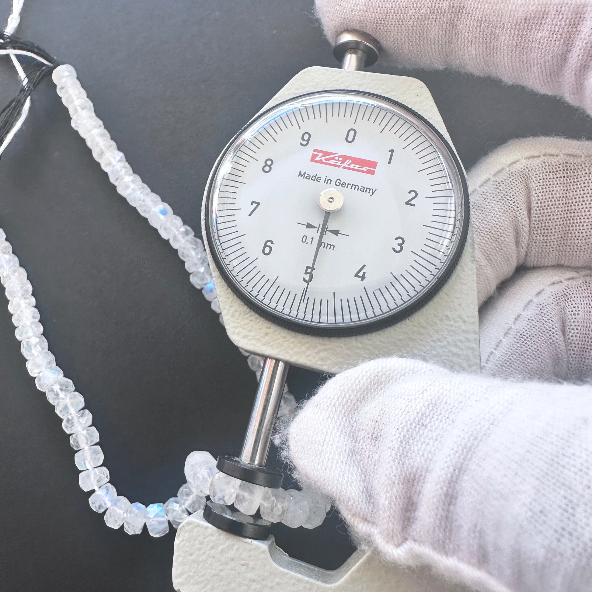A dial gauge measures the Moonstone faceted rondelle 5mm gemstone.