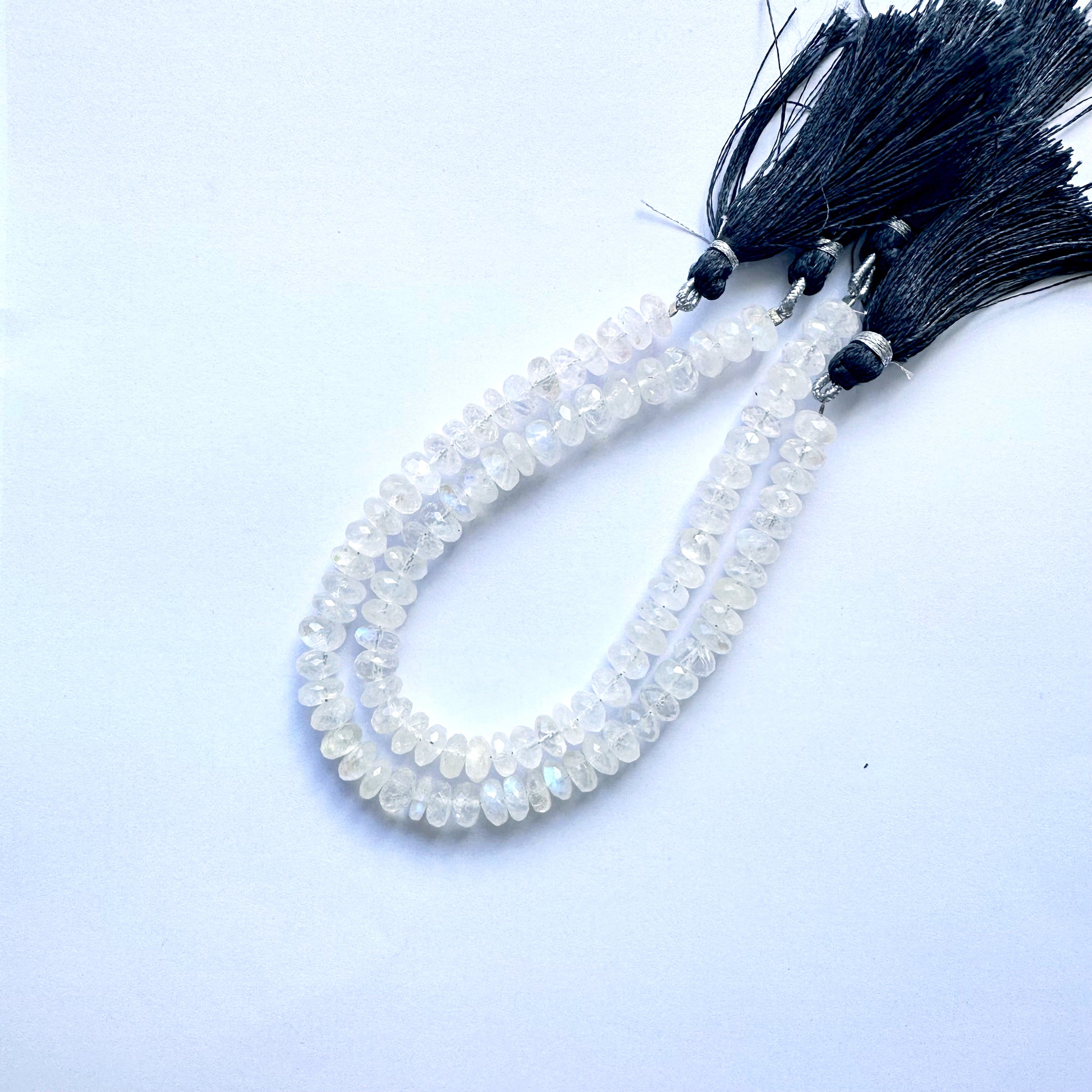 Gleaming moonstone rondelle gemstones arranged in a uniform pattern on thread.