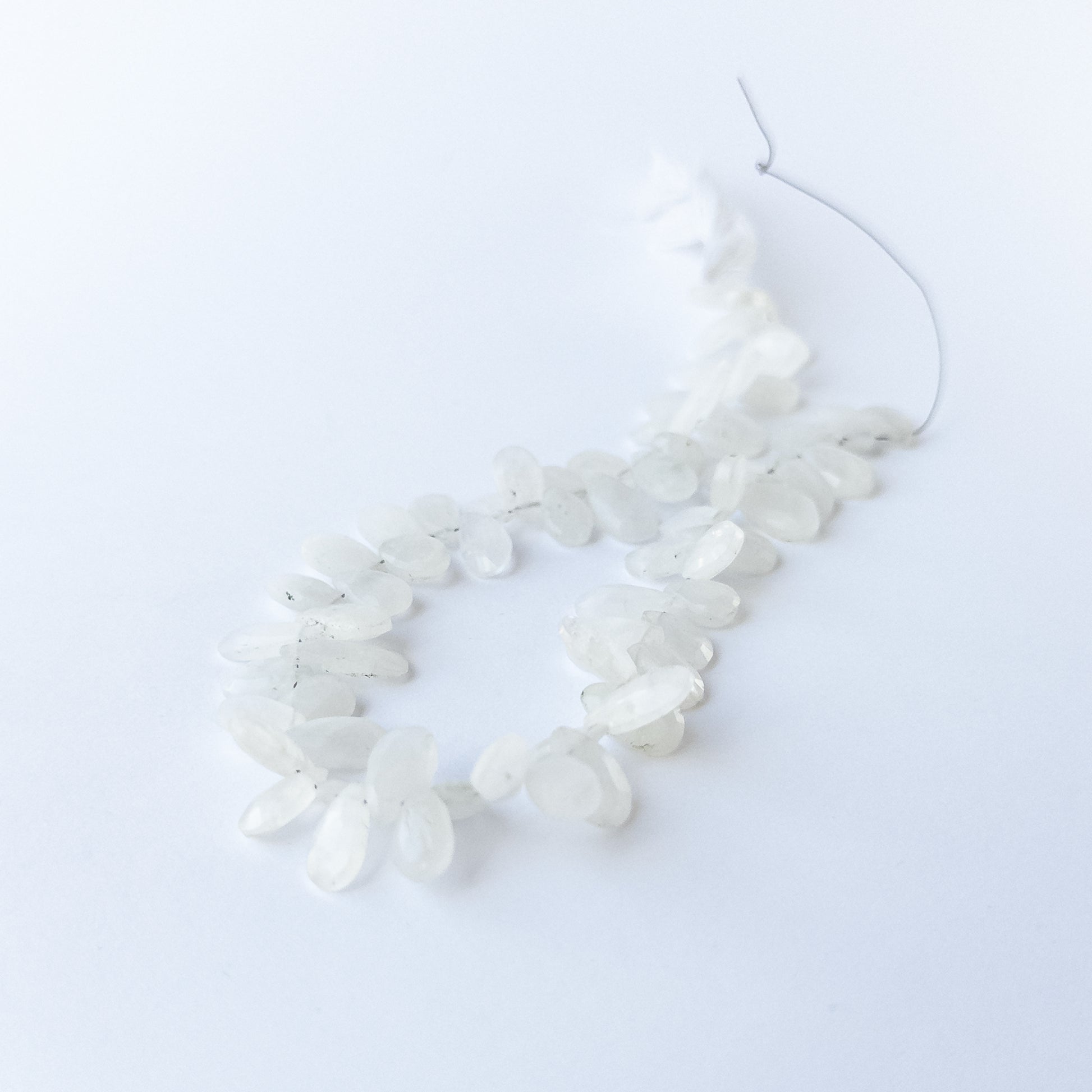 Authentic Rainbow Moonstone gemstone beads with faceted briolette cut arranged neatly in a 28cm strand.