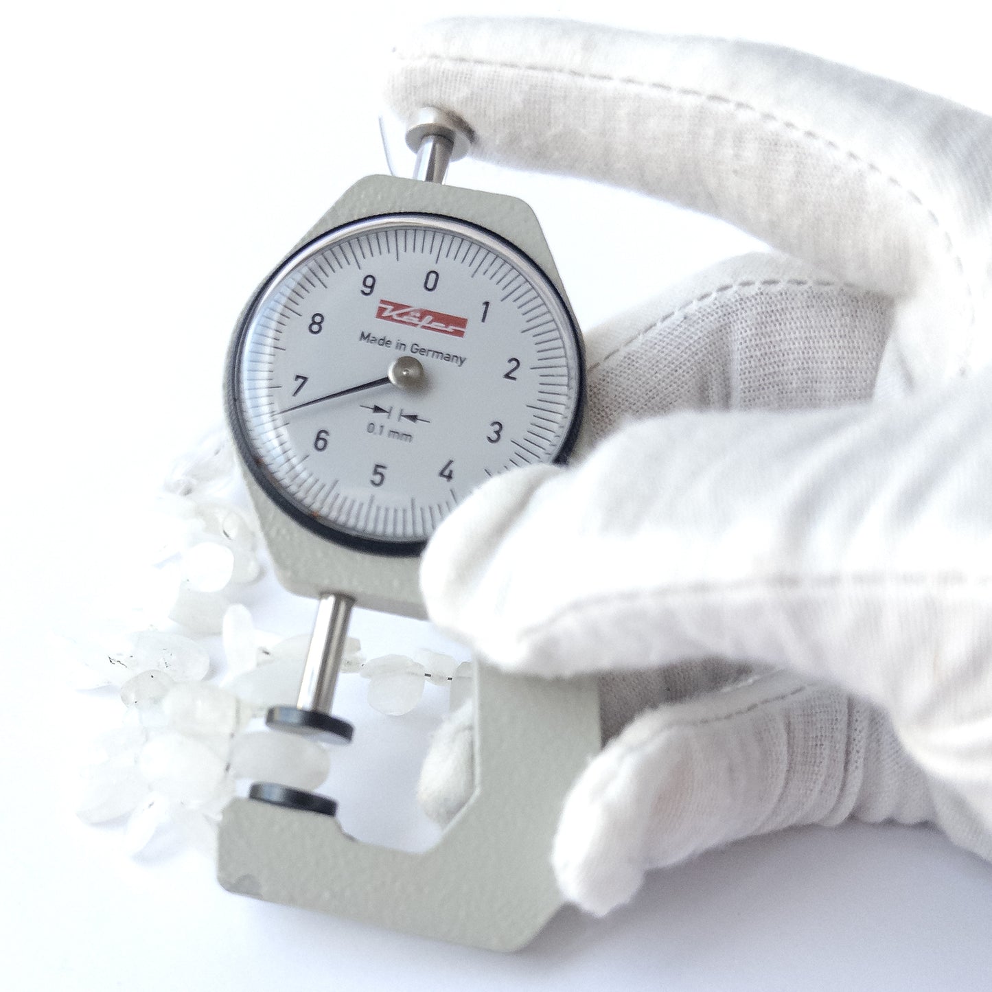 A dial gauge measures the Rainbow Moonstone faceted briolette 6.5–7mm gemstone.