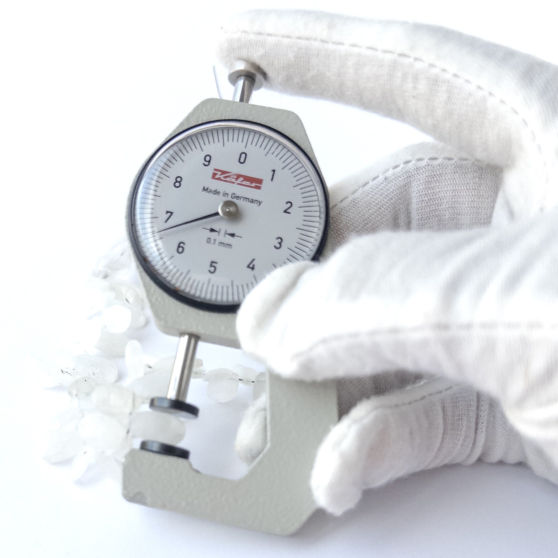 A dial gauge measures the Rainbow Moonstone faceted briolette 6.5–7mm gemstone.