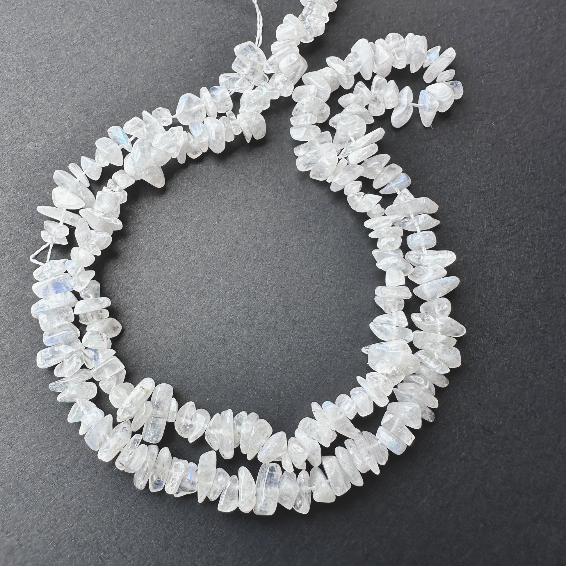 Close-up of Moonstone smooth chip beads with soft white tones and subtle blue flashes.