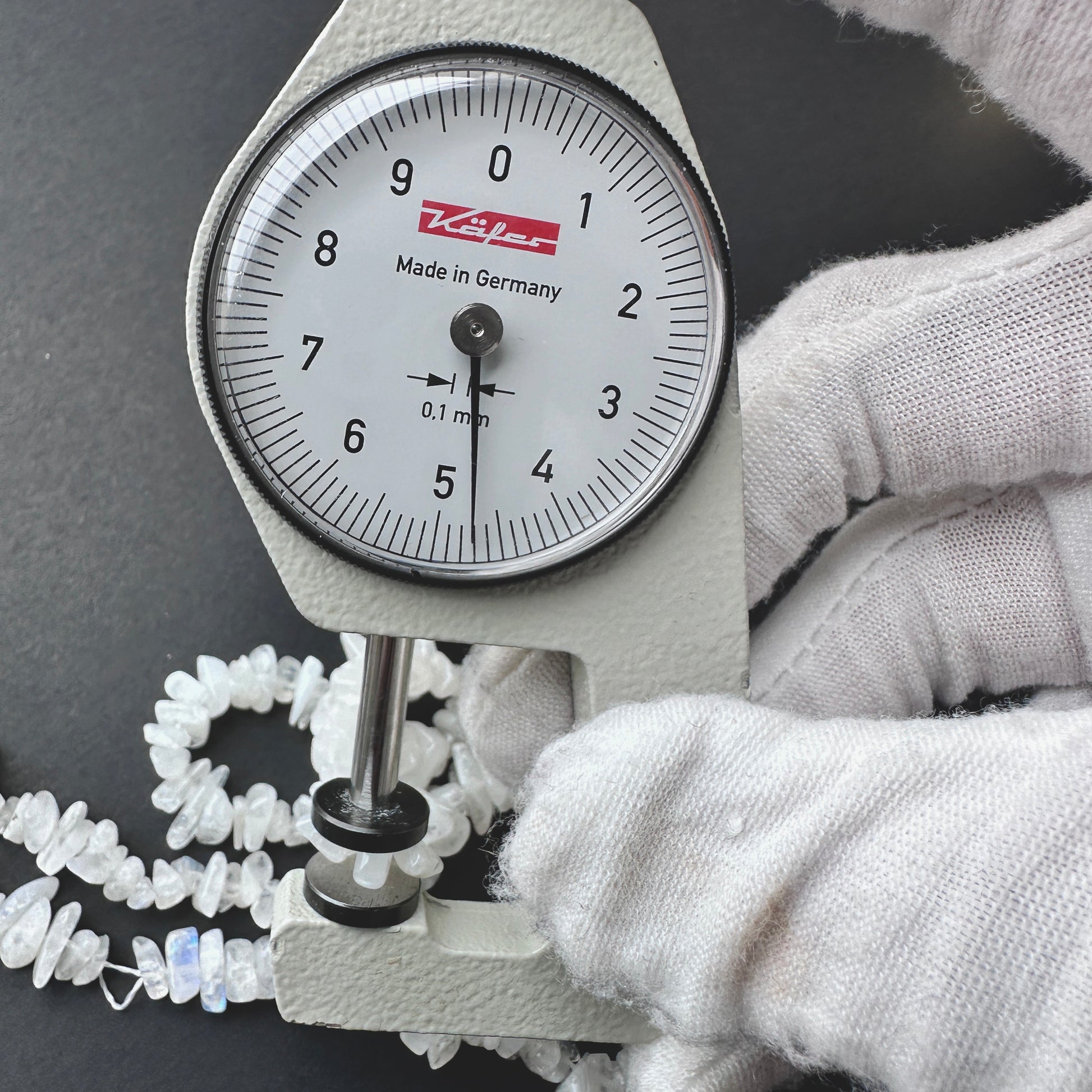 A dial gauge measures the Moonstone smooth chip 4-6mm gemstone.
